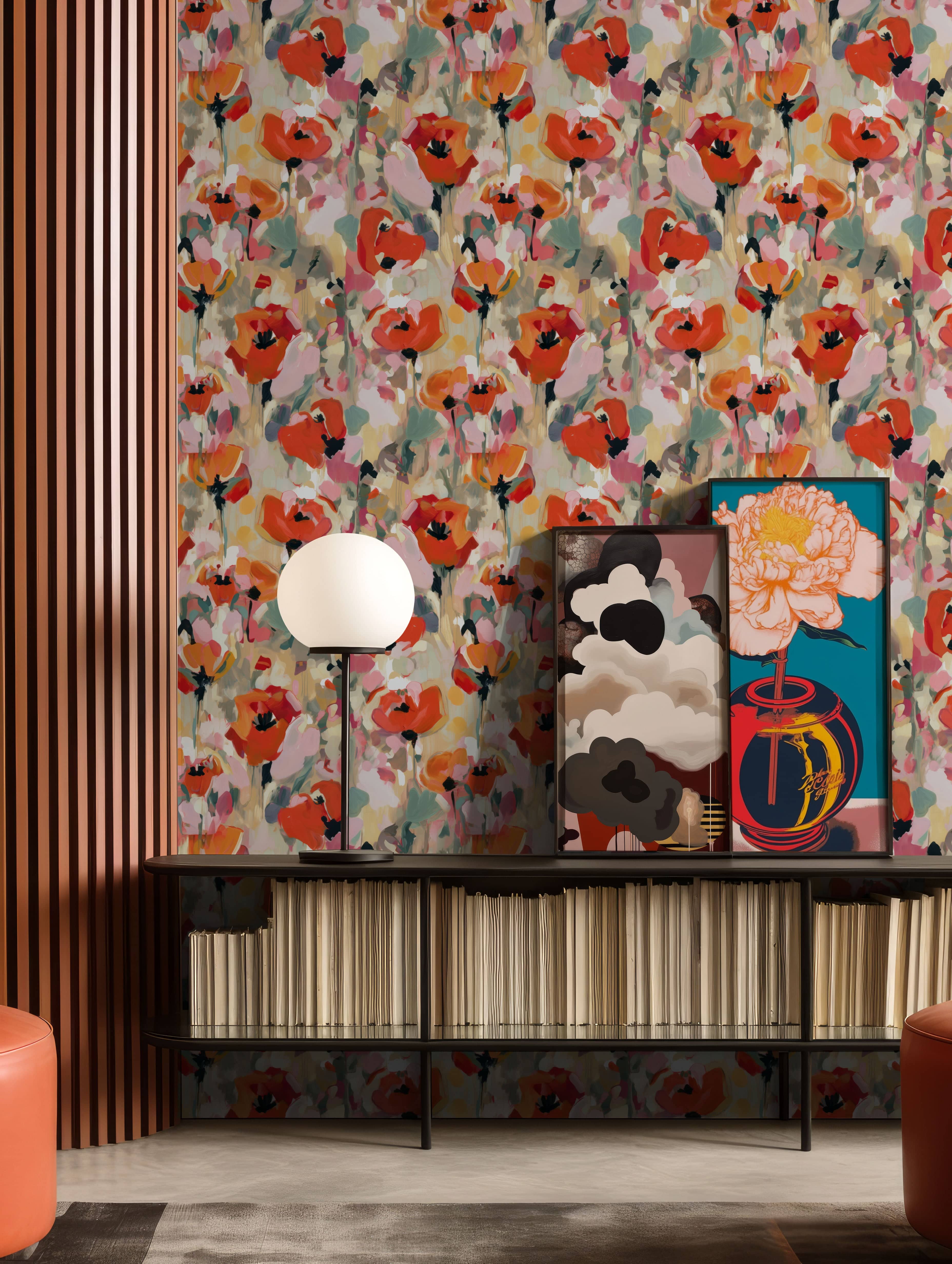 Painterly floral wallpaper with red and blush poppy-style blooms, styled in a modern interior with framed artwork, a sculptural table lamp, and a low shelving unit.