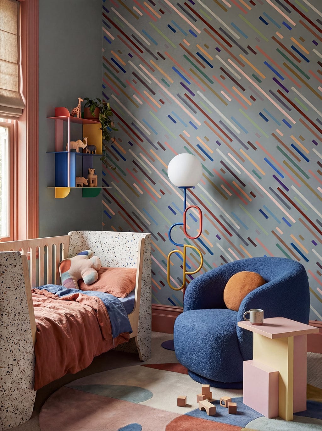 Children's room with colorful wall pattern, blue chair, and toys.