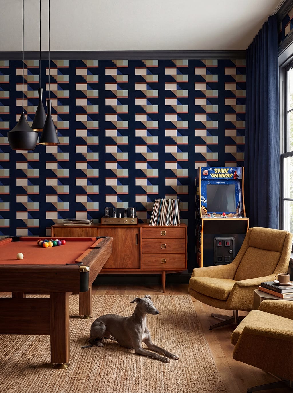 Living room with pool table, arcade machine, and geometric wall design.