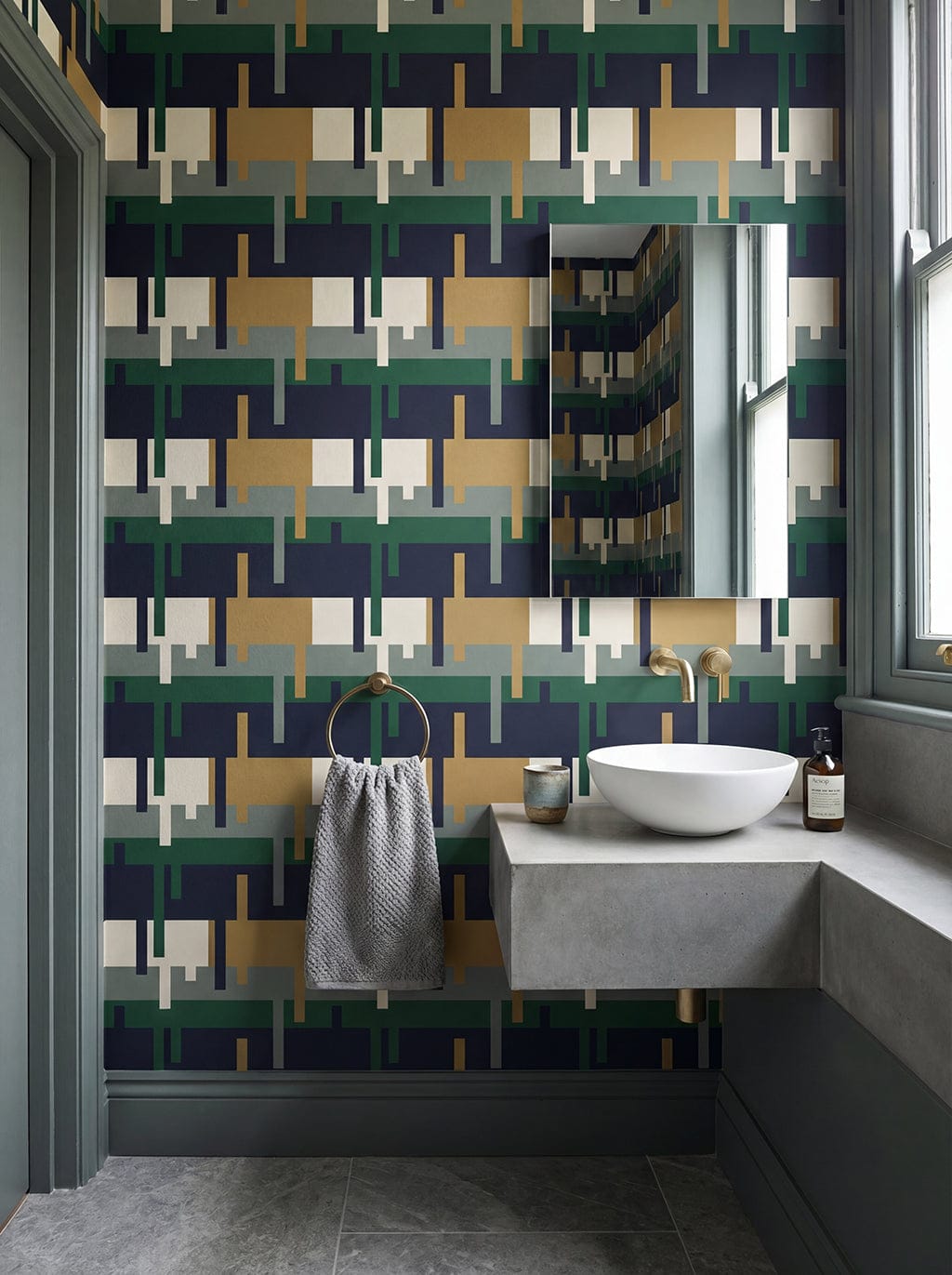 Bathroom with geometric patterned wallpaper, sink, and towel.