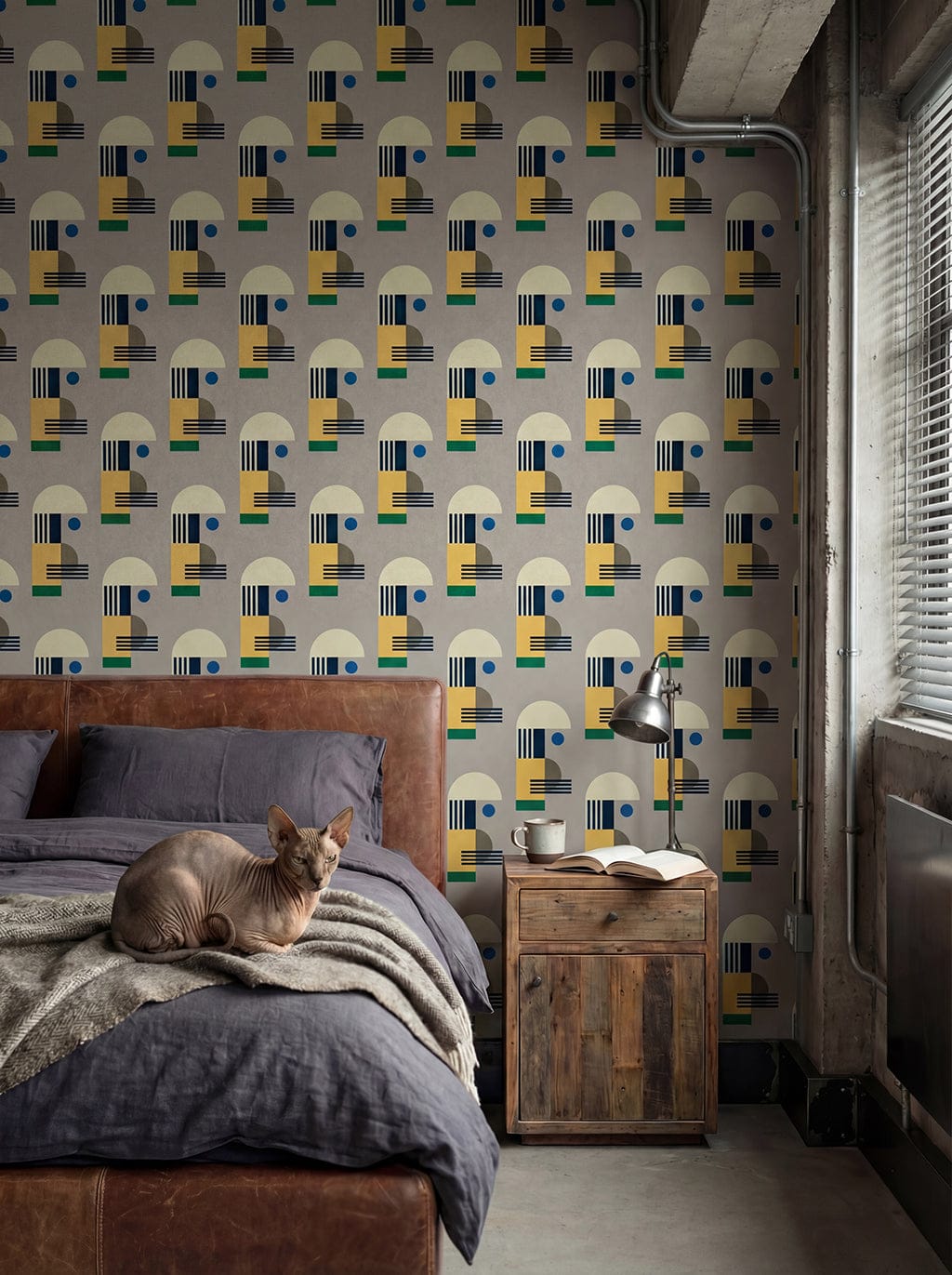Bedroom with geometric patterned wallpaper, wooden nightstand, and cat on bed.