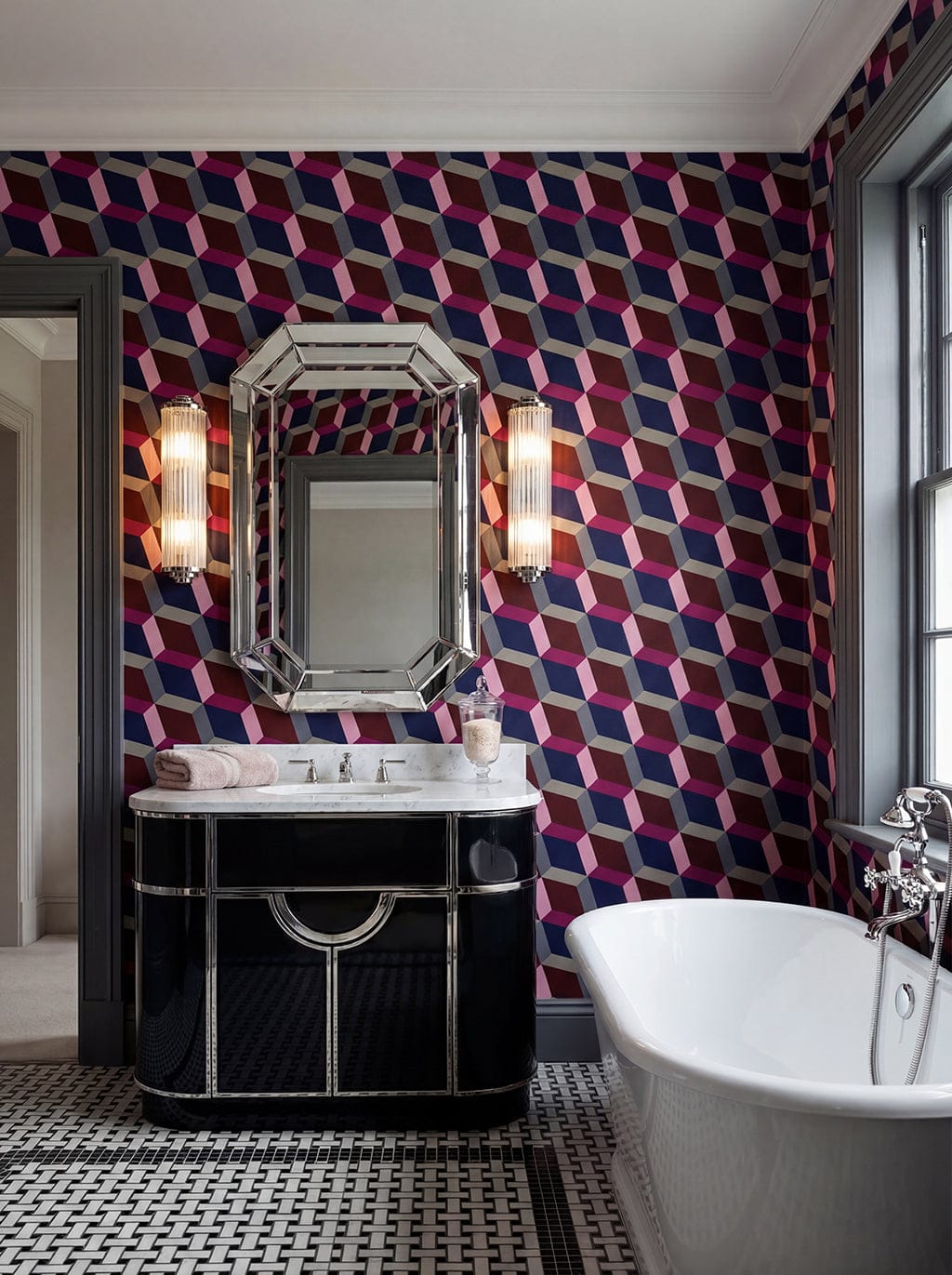 Bathroom with geometric patterned wallpaper, black vanity, and white freestanding bathtub.