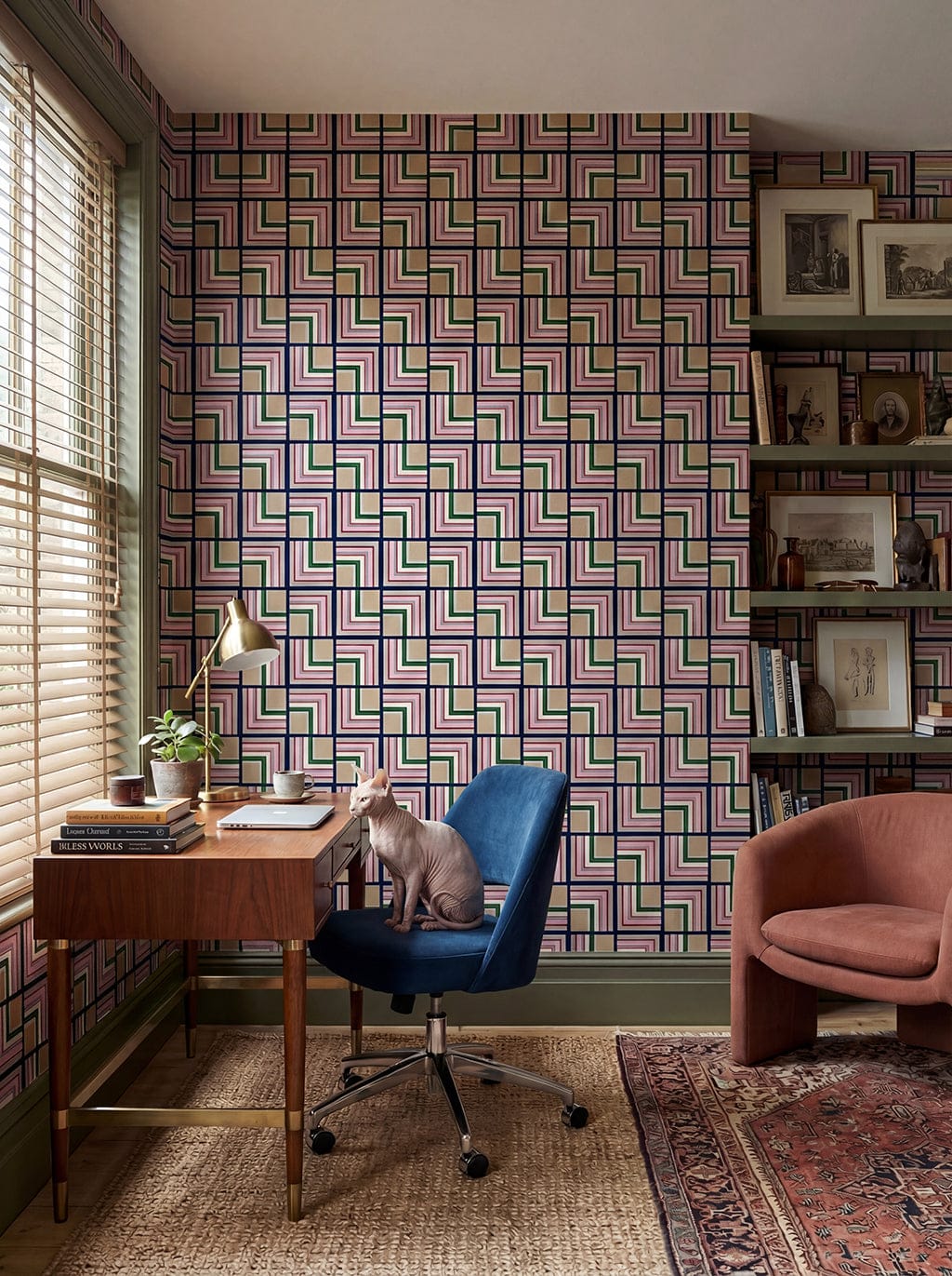 Home office with geometric patterned wall, desk, chair, and bookshelf.